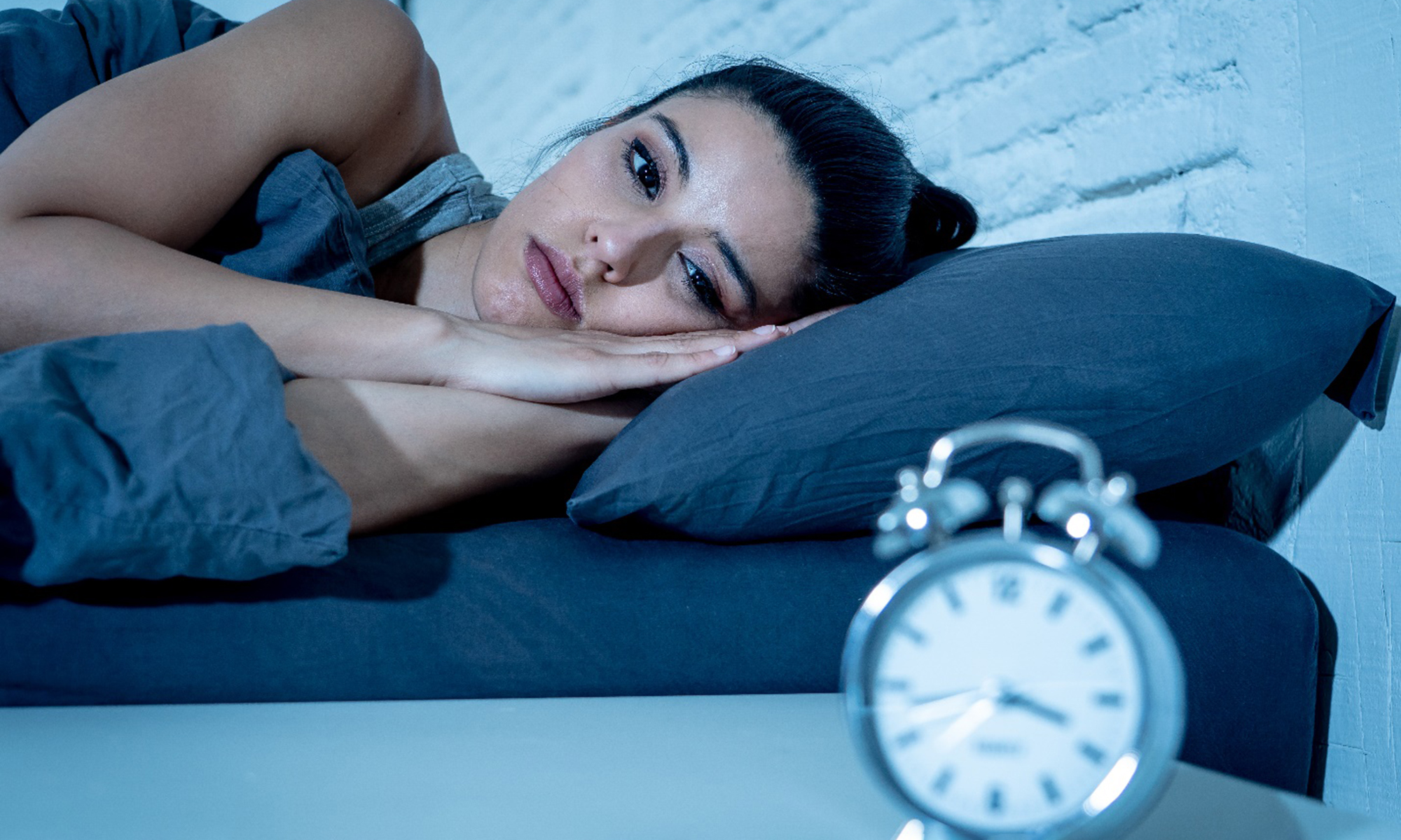 Woman staring at clock from bed
